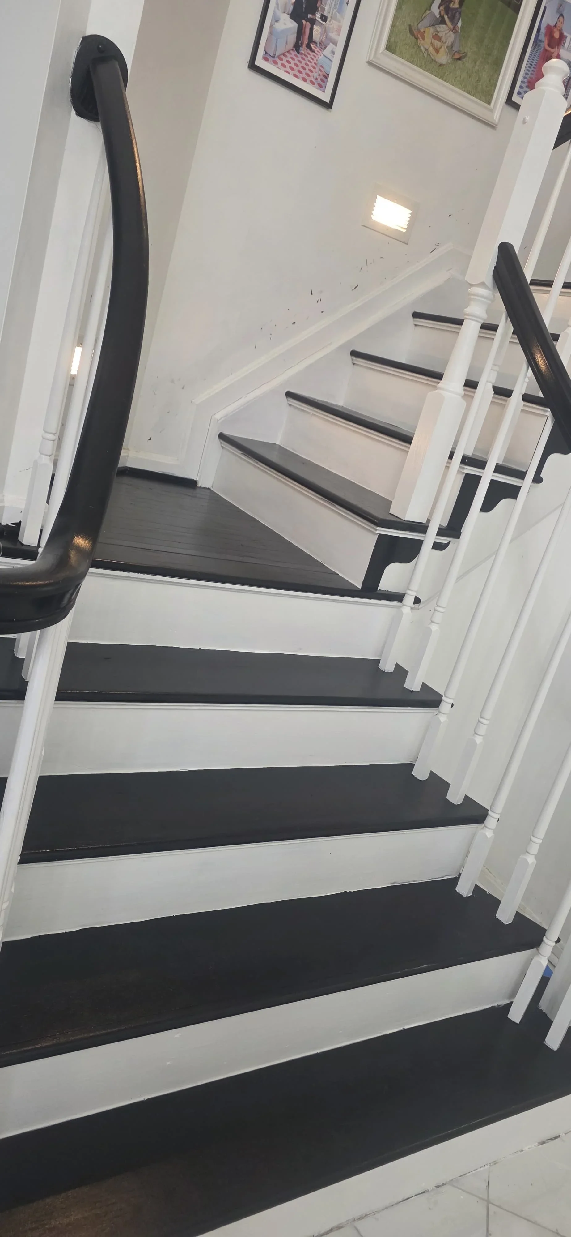 Modern staircase with white painted stringers, black tread runners, and black metal railings