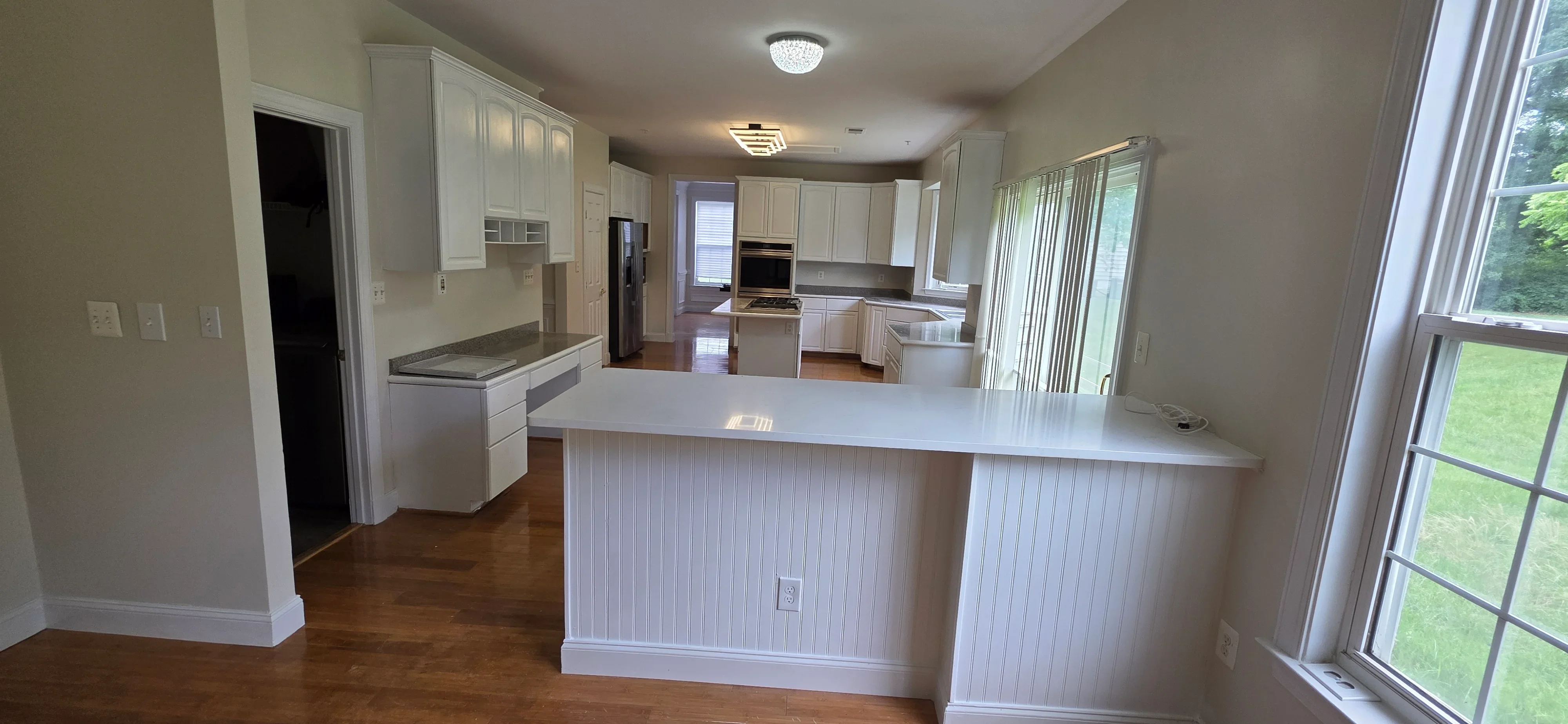 Modern kitchen with white cabinetry, large island, and hardwood floors