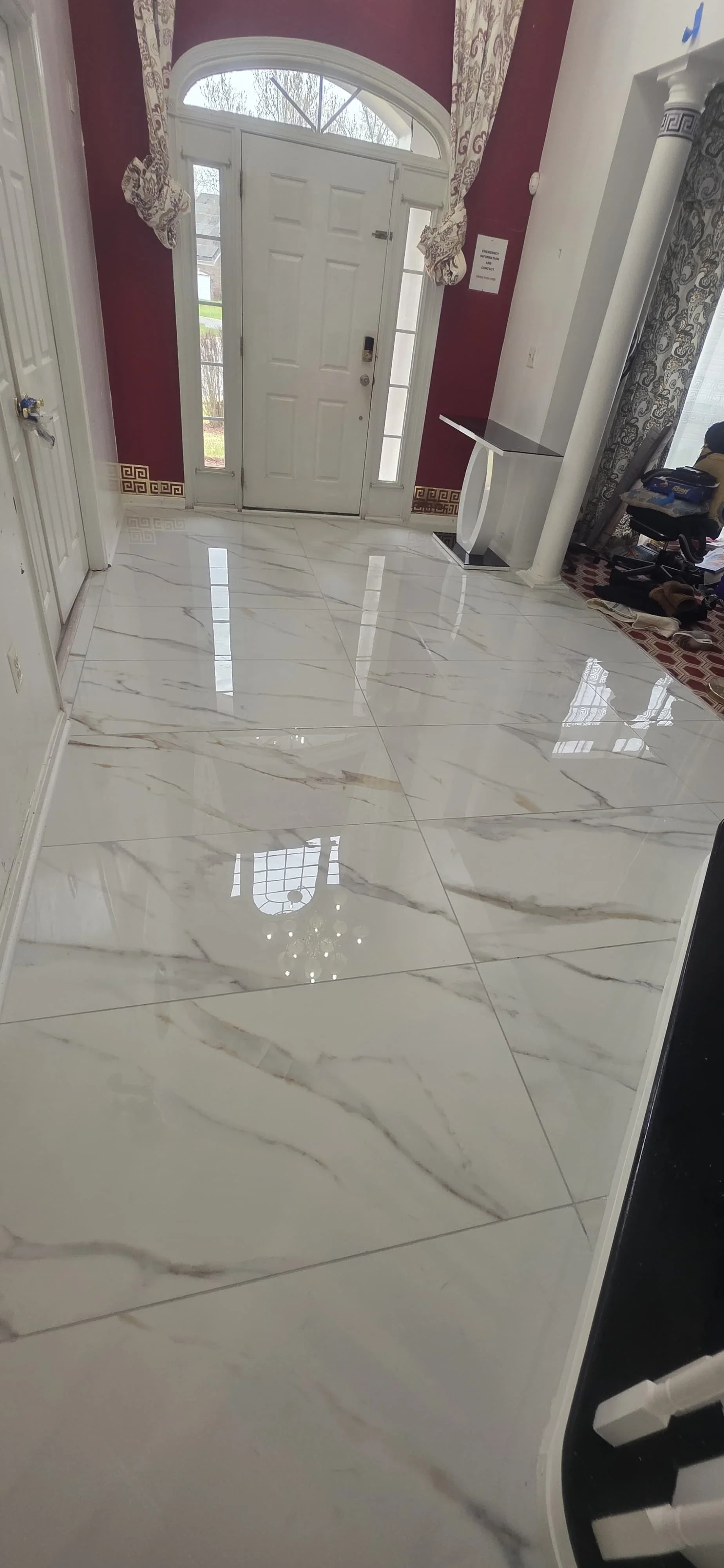 Polished marble tile foyer with gray veining, white entry door, and burgundy walls