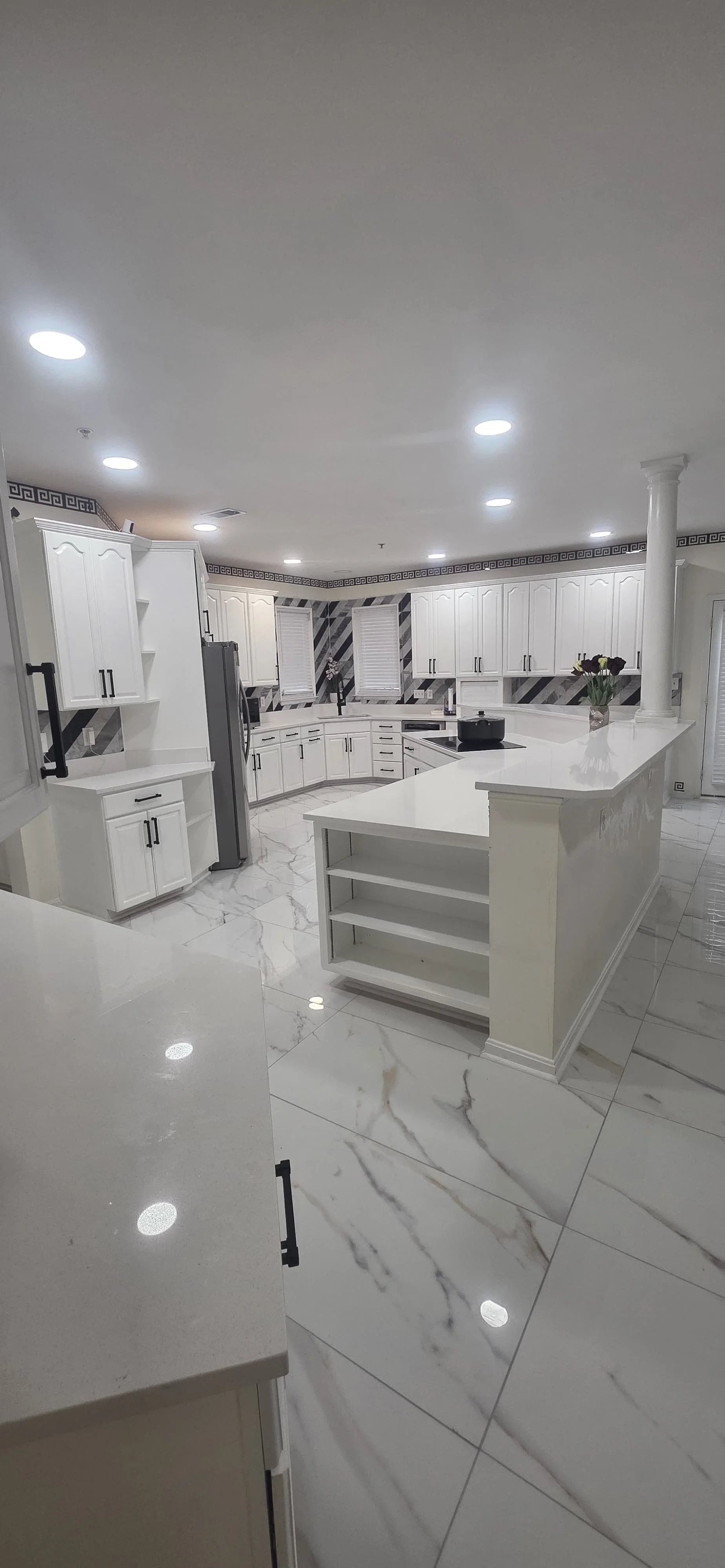 Modern white kitchen with marble flooring, white cabinetry, and center island