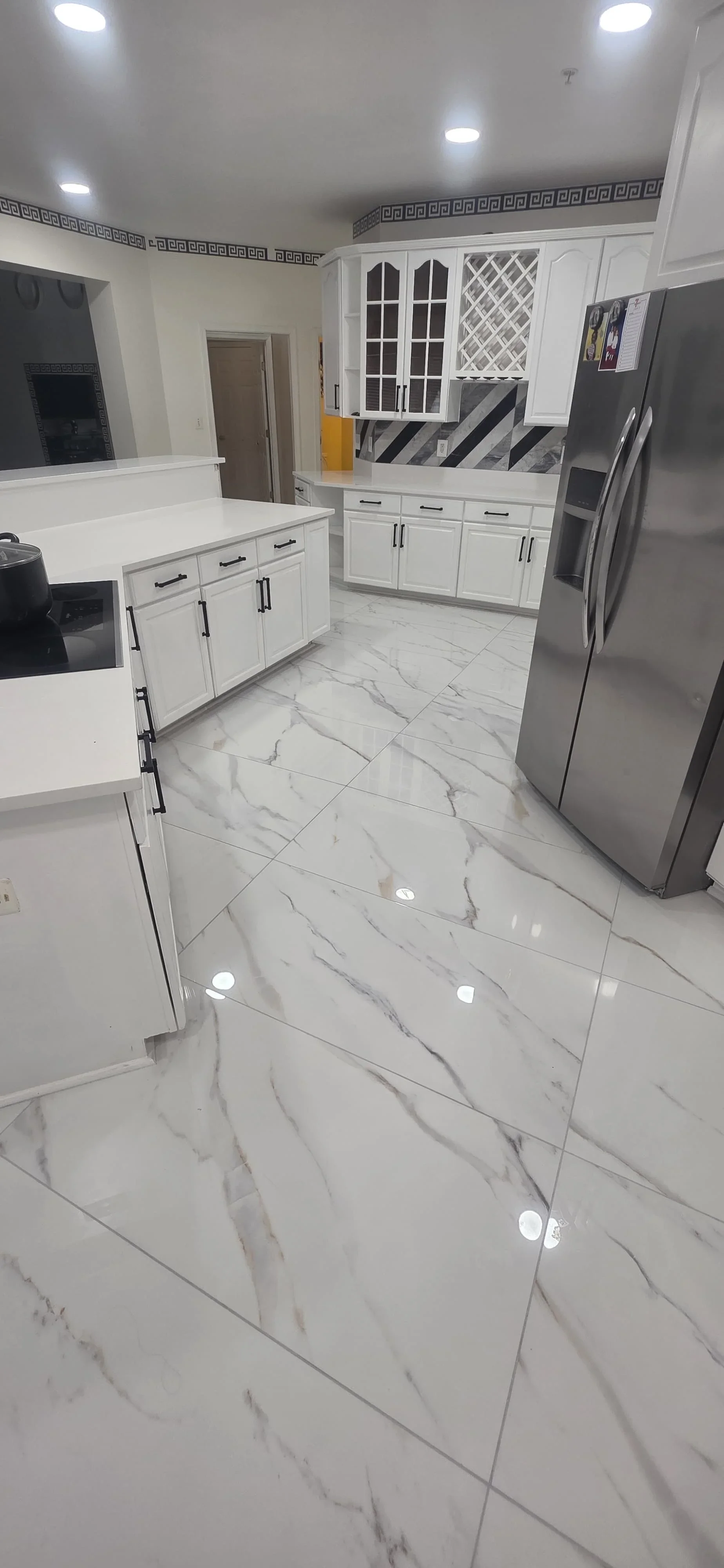 Modern kitchen with white cabinets, marble tile flooring, stainless steel appliances, and recessed lighting