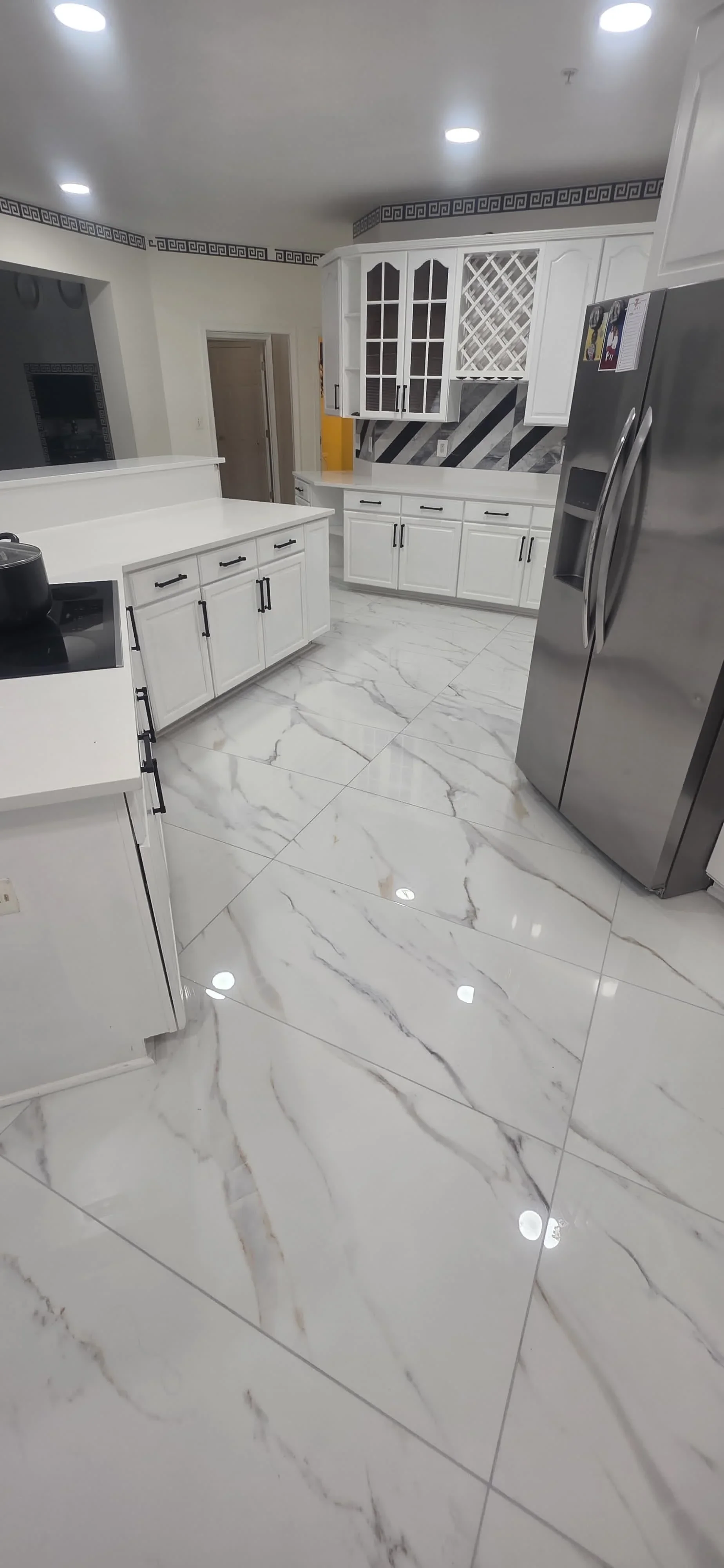 Modern kitchen with white cabinets, marble tile flooring, stainless steel appliances, and recessed lighting