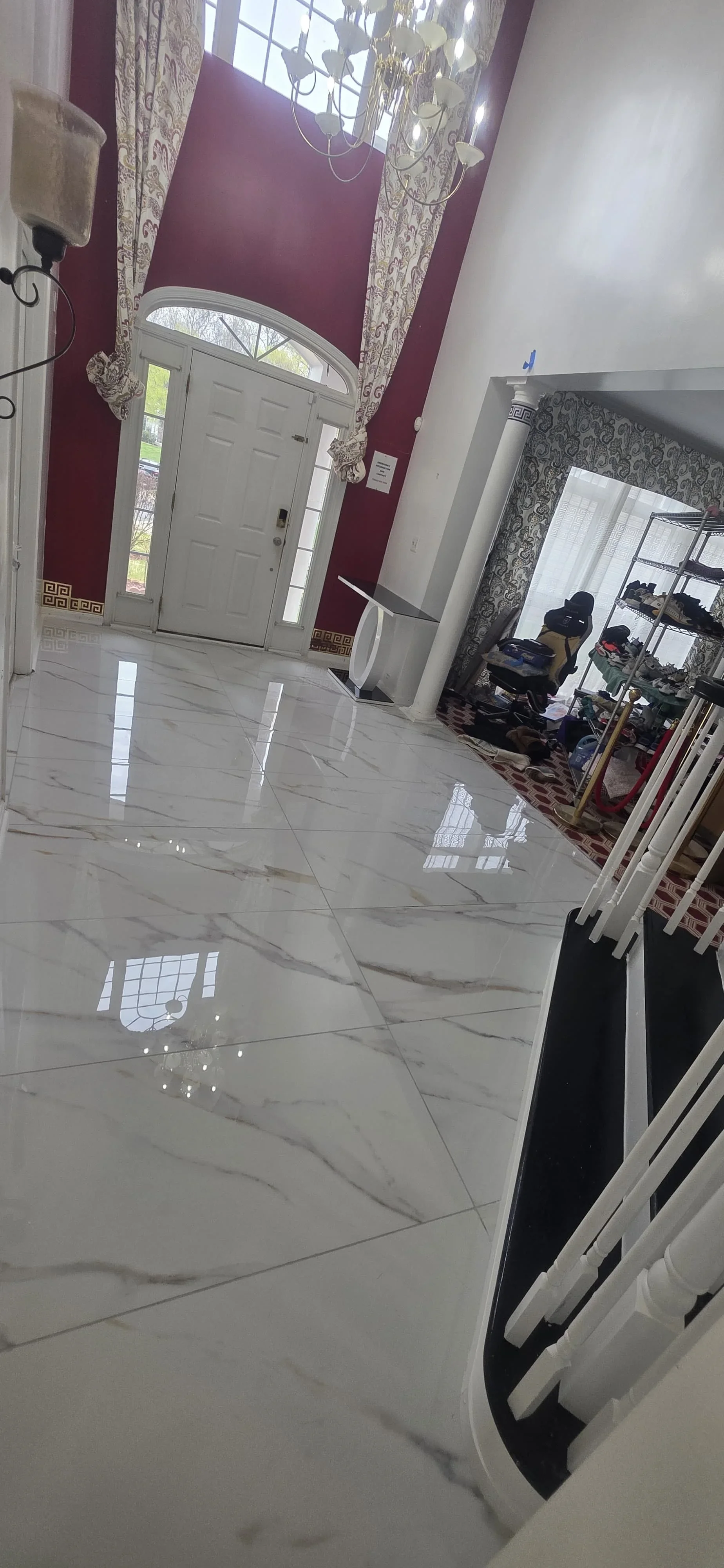 Polished marble tile foyer with gray veining, arched doorway, and burgundy walls
